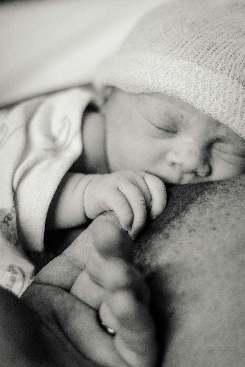 grayscale photo of man and woman kissing babys leg