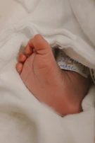 A close-up of tiny baby feet resting on a soft hospital blanket, symbolizing new life.