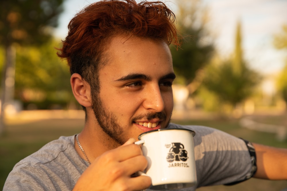 man in gray crew neck shirt holding white ceramic mug