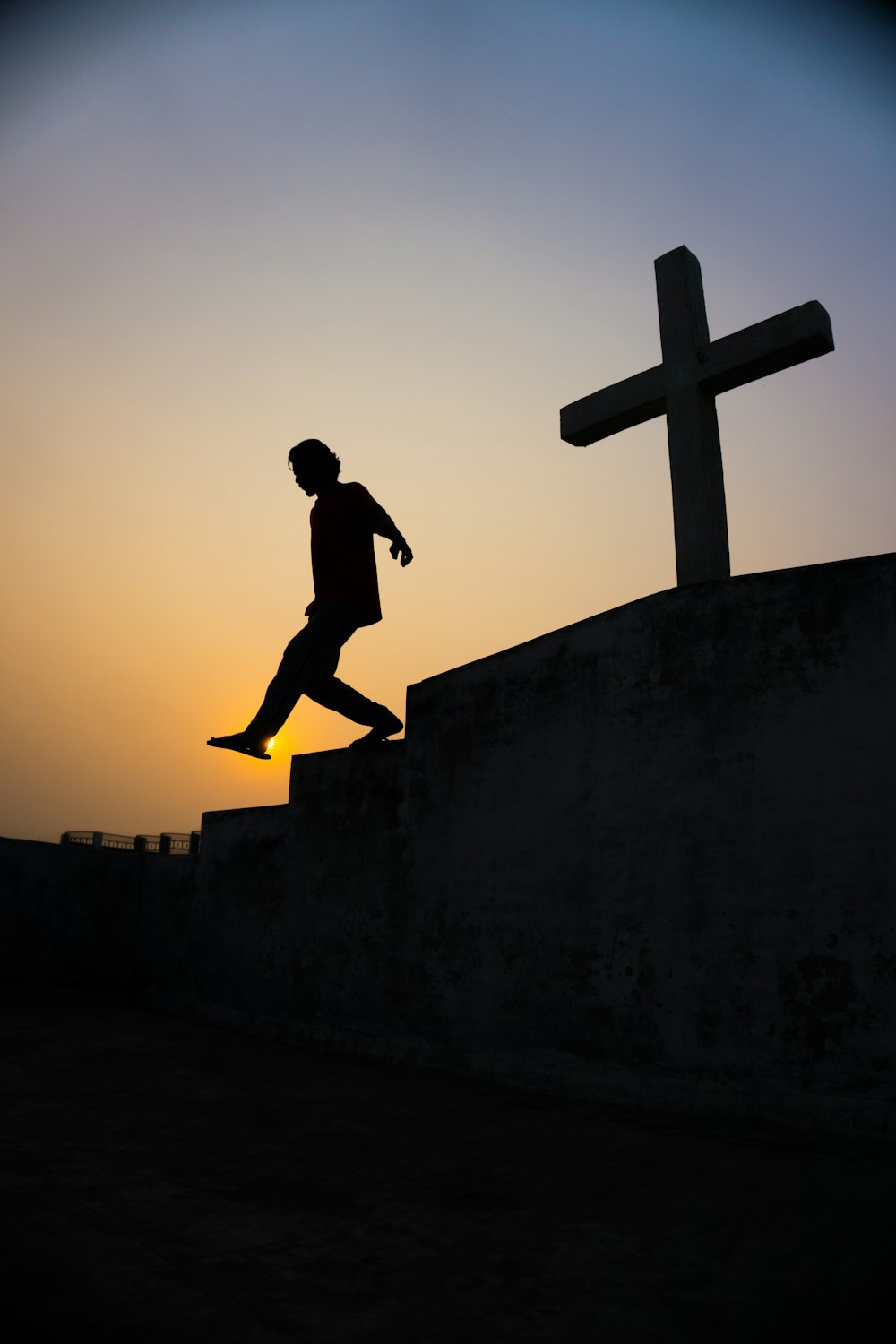 Silueta del hombre saltando sobre la pared de hormigón durante la puesta del sol