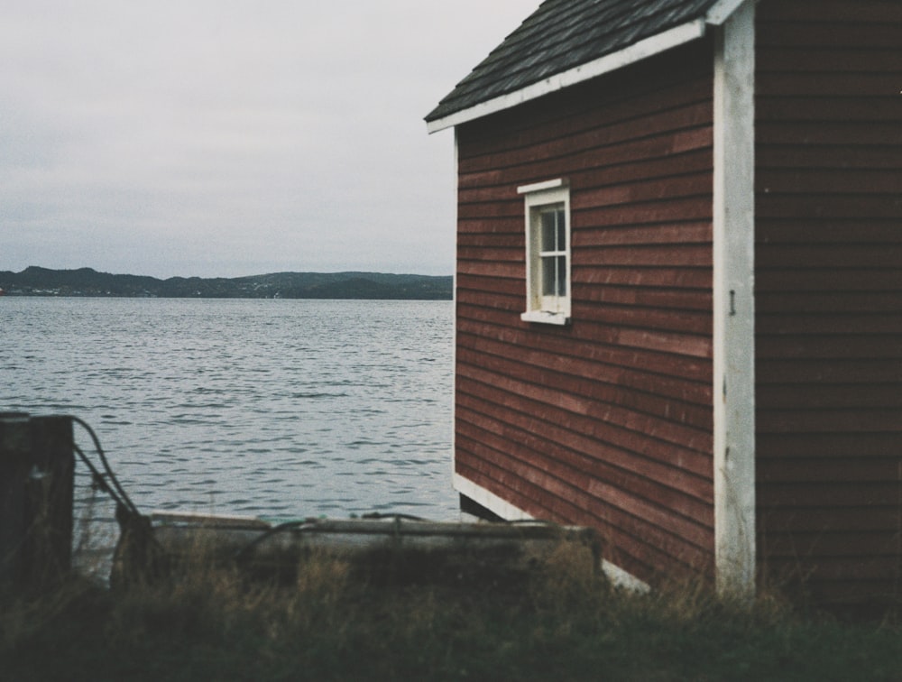 brown wooden house near body of water during daytime