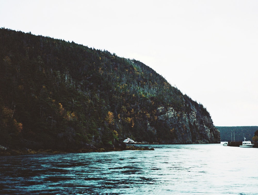 green and brown mountain beside body of water during daytime