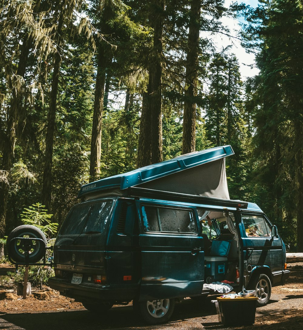 black suv on dirt road in between trees during daytime