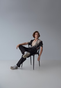 woman in black shirt and white pants sitting on white seat