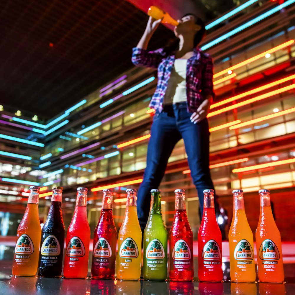 woman in blue and white plaid shirt and blue denim jeans holding coca cola bottles