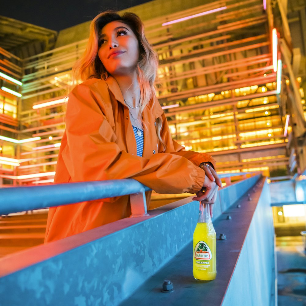 woman in pink coat holding green plastic bottle