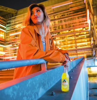 woman in pink coat holding green plastic bottle