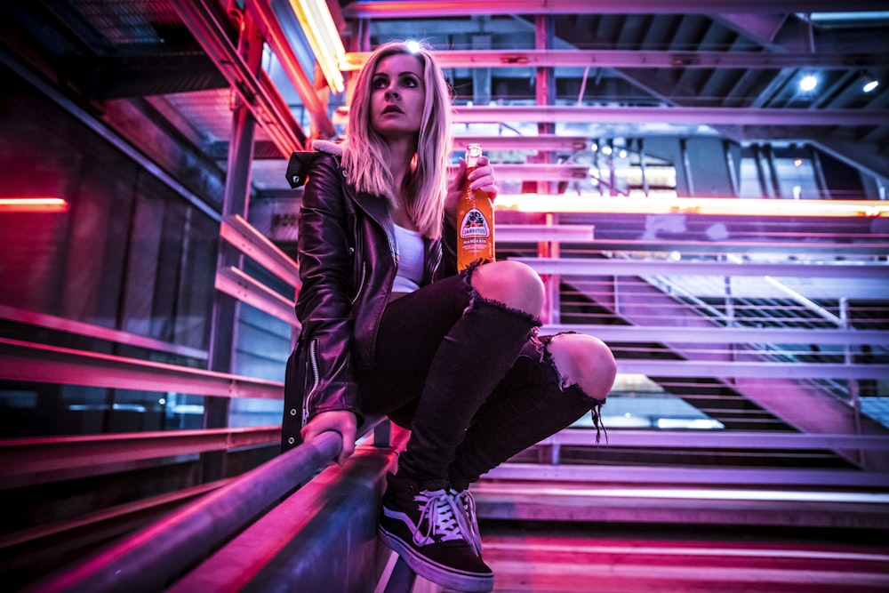 woman in black leather jacket leaning on gray metal railings