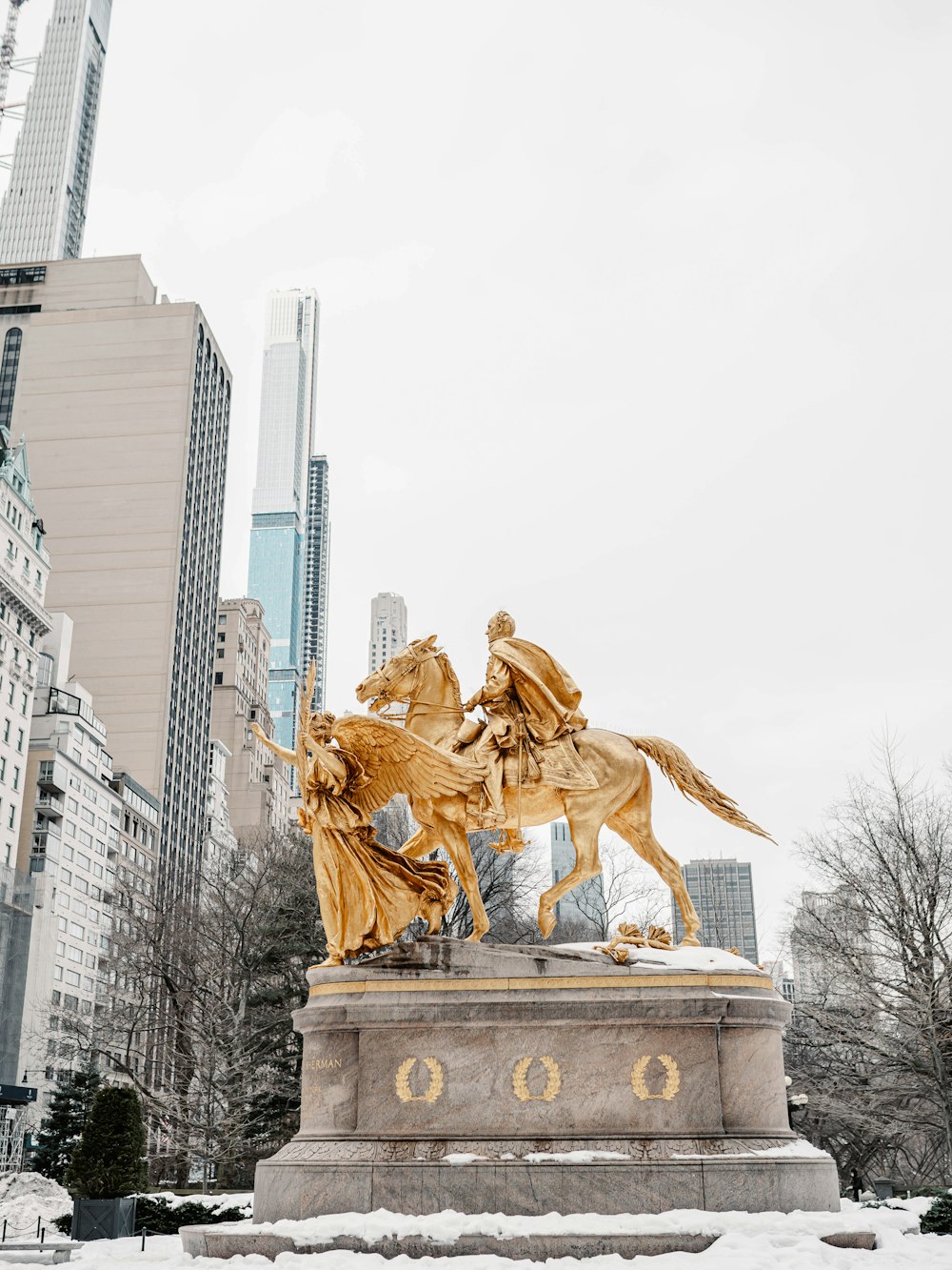 gold statue of man riding horse near high rise buildings during daytime