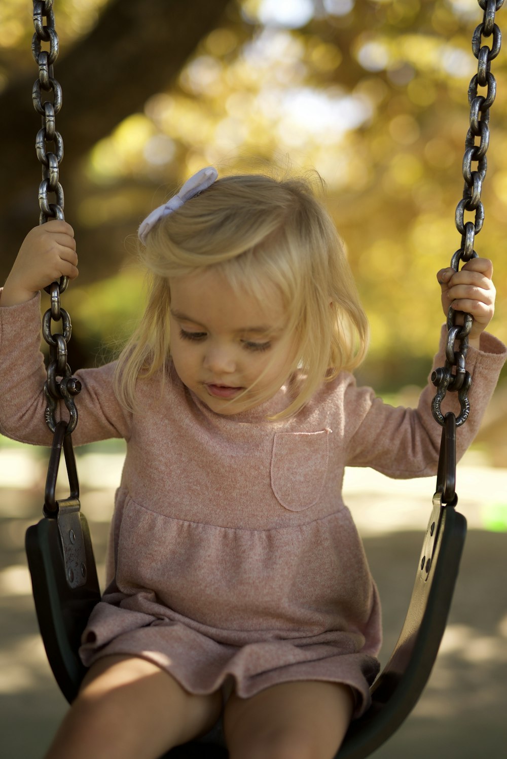 girl in pink long sleeve shirt on swing during daytime