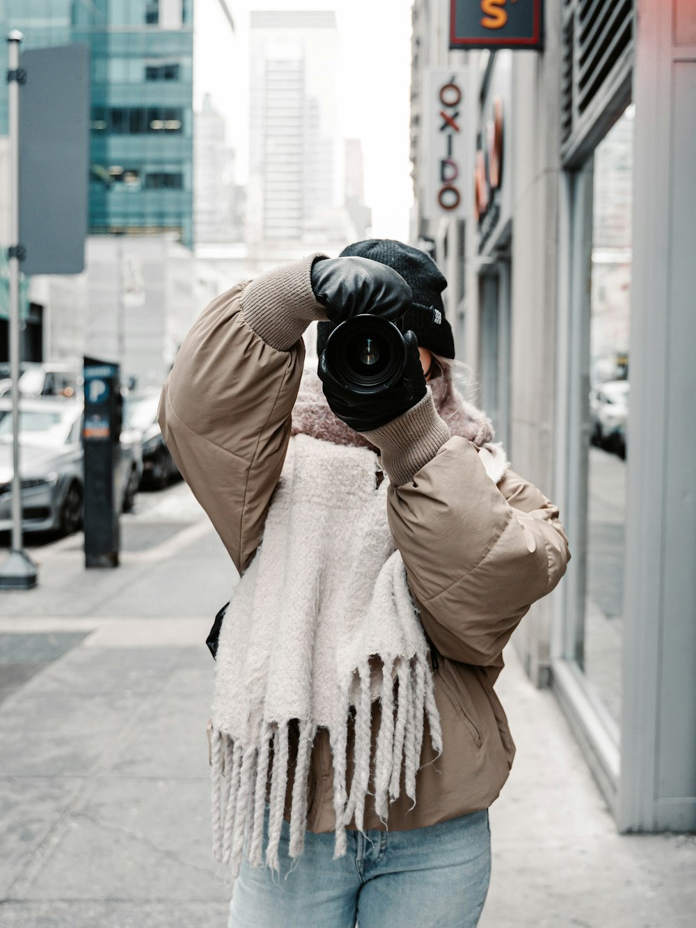 person in brown coat holding black dslr camera
