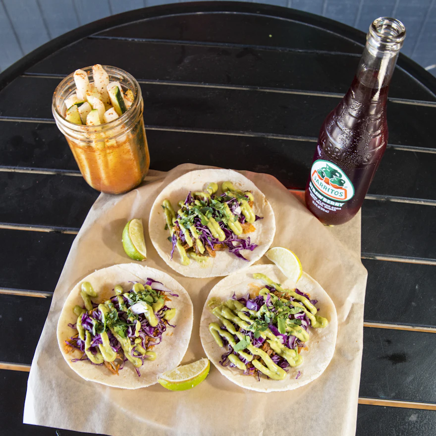 A plate of fresh Mexican tacos served with lime and salsas