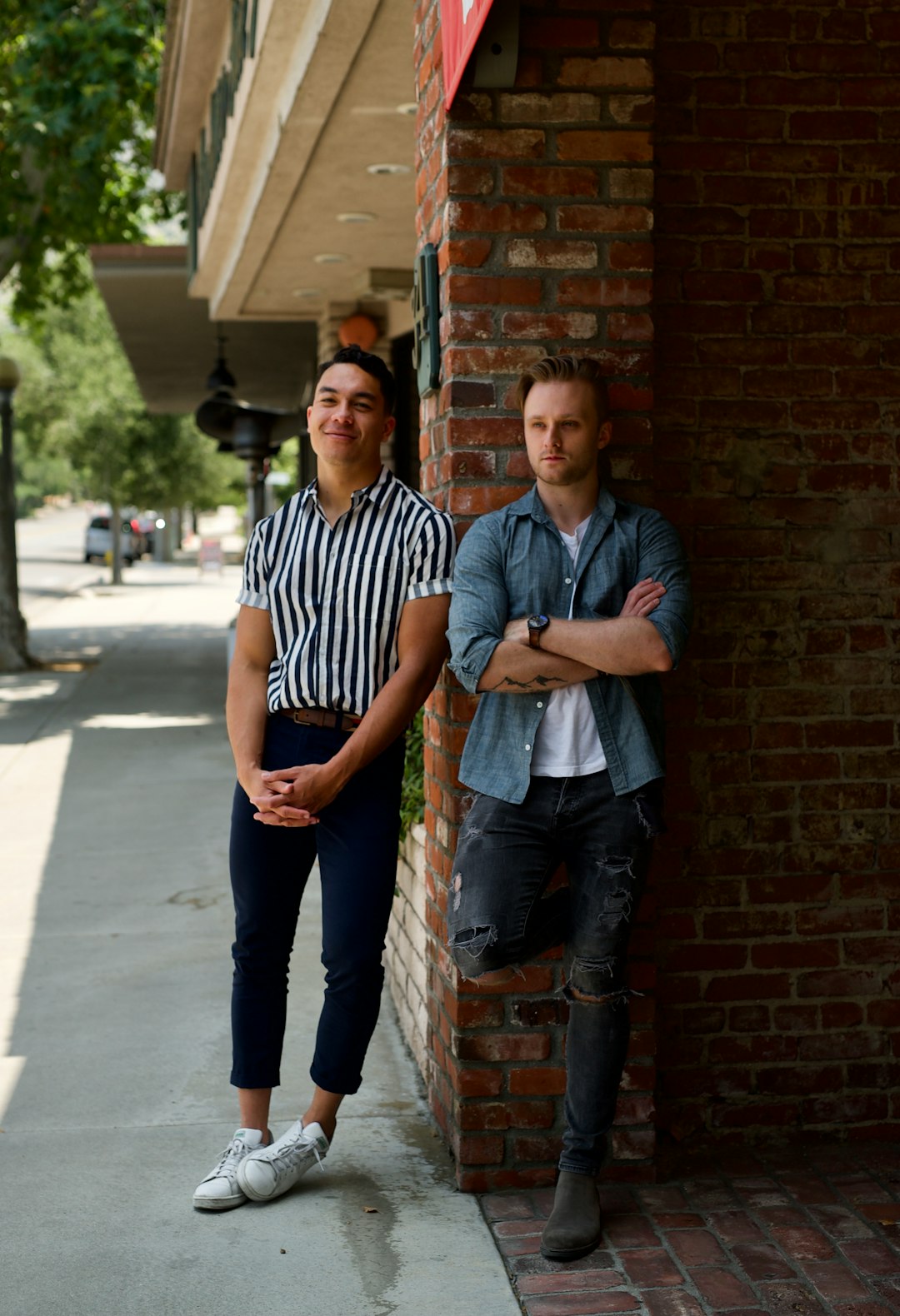 man in blue and white striped polo shirt standing beside man in blue denim jeans