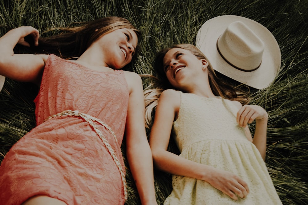 2 women lying on grass field