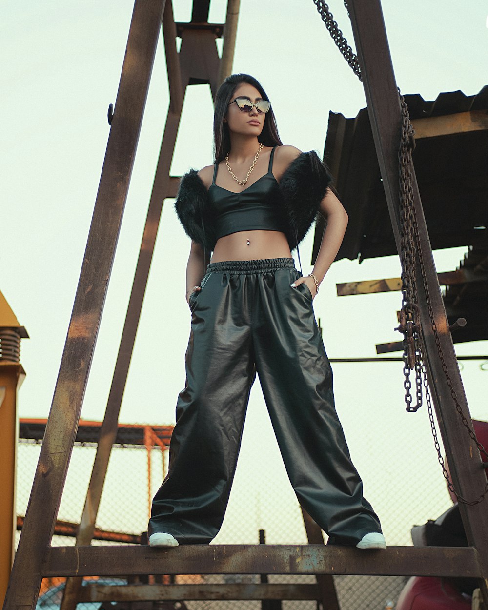 woman in black brassiere and black pants standing under brown wooden post during daytime