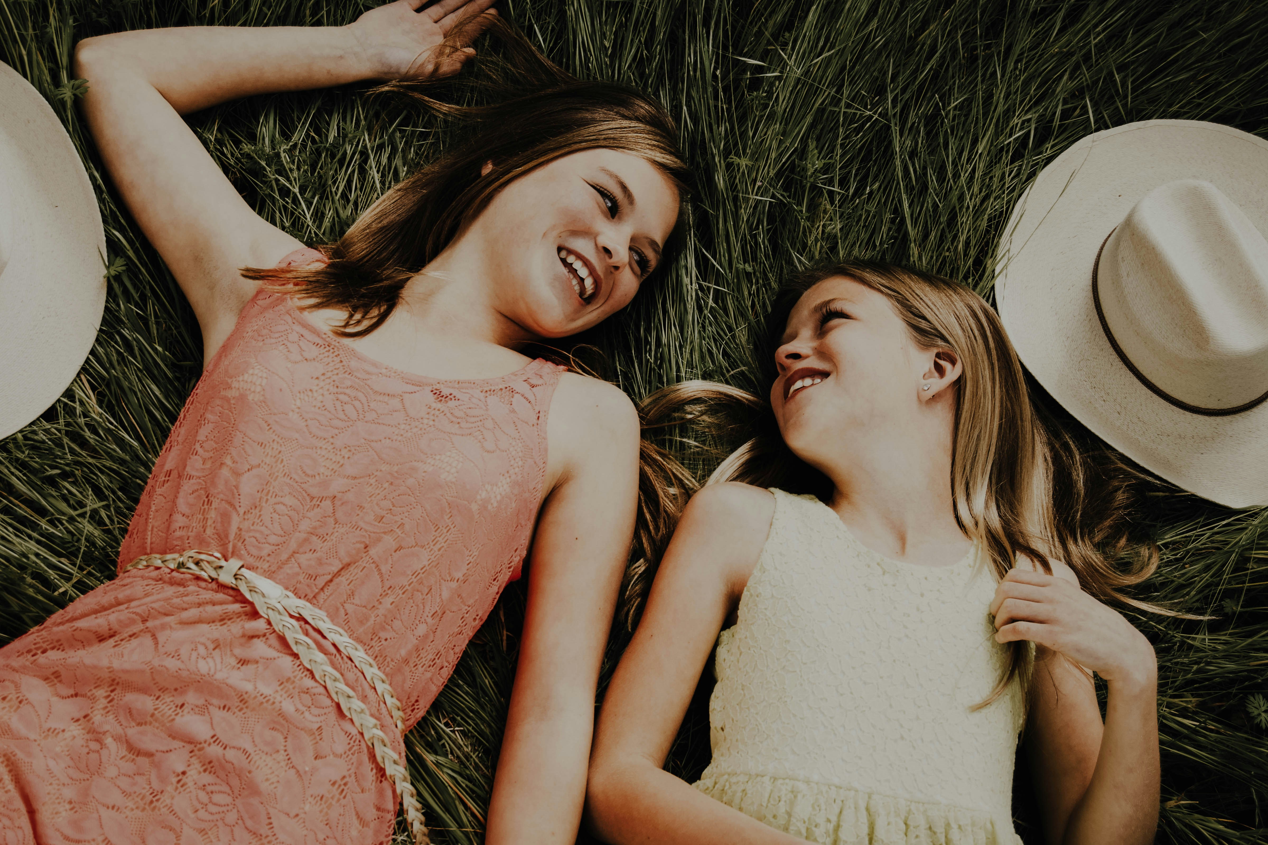 2 women lying on grass field