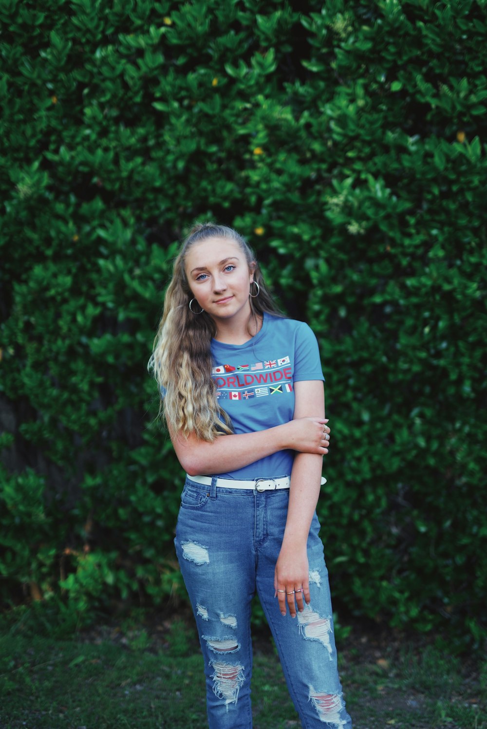 woman in purple and white crew neck t-shirt and blue denim jeans standing near green