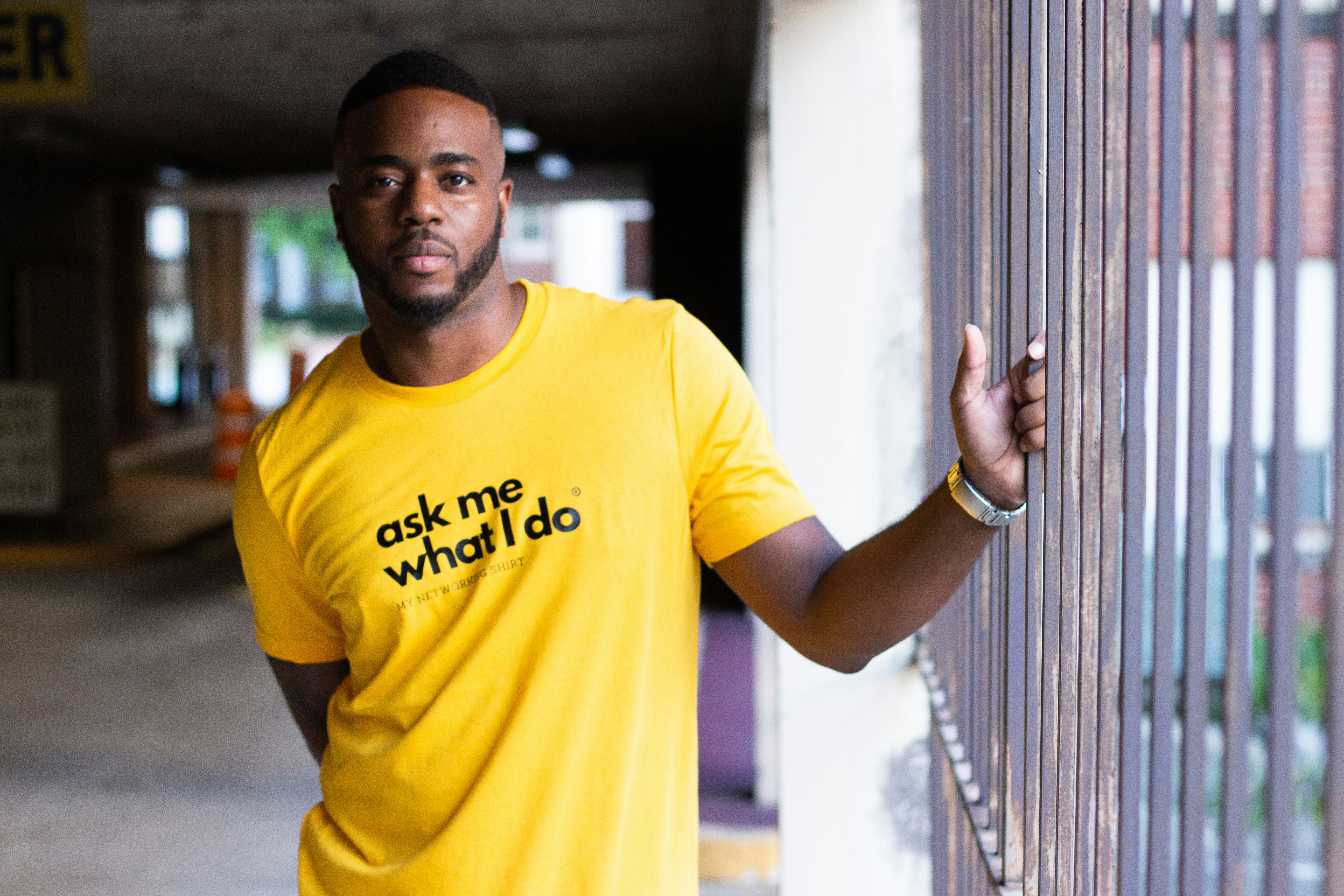man in yellow crew neck t-shirt leaning on white wall, 