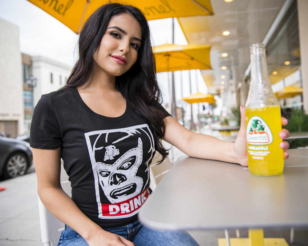 woman in black crew neck t-shirt sitting on white table