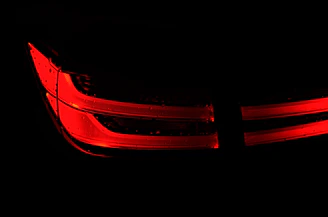 Bright LED car lights glowing against a sleek black vehicle at dusk.