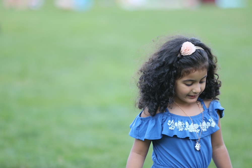 girl in blue dress standing on green grass field during daytime