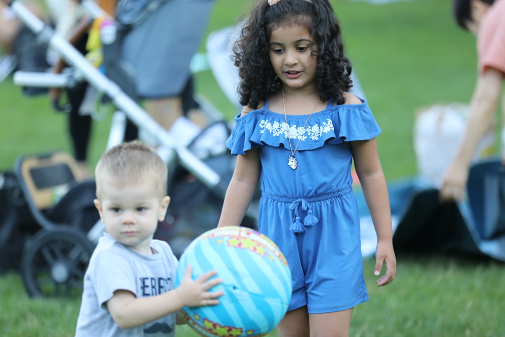 girl in blue dress holding boy in blue shirt during daytime