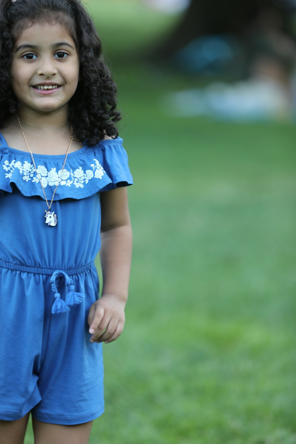 girl in blue dress standing on green grass field during daytime