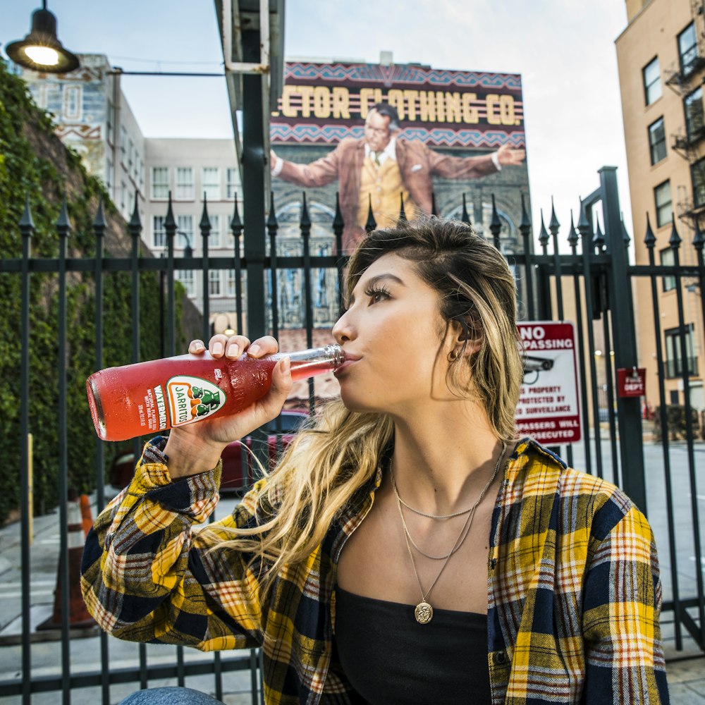 woman in yellow and black plaid button up shirt drinking red plastic cup