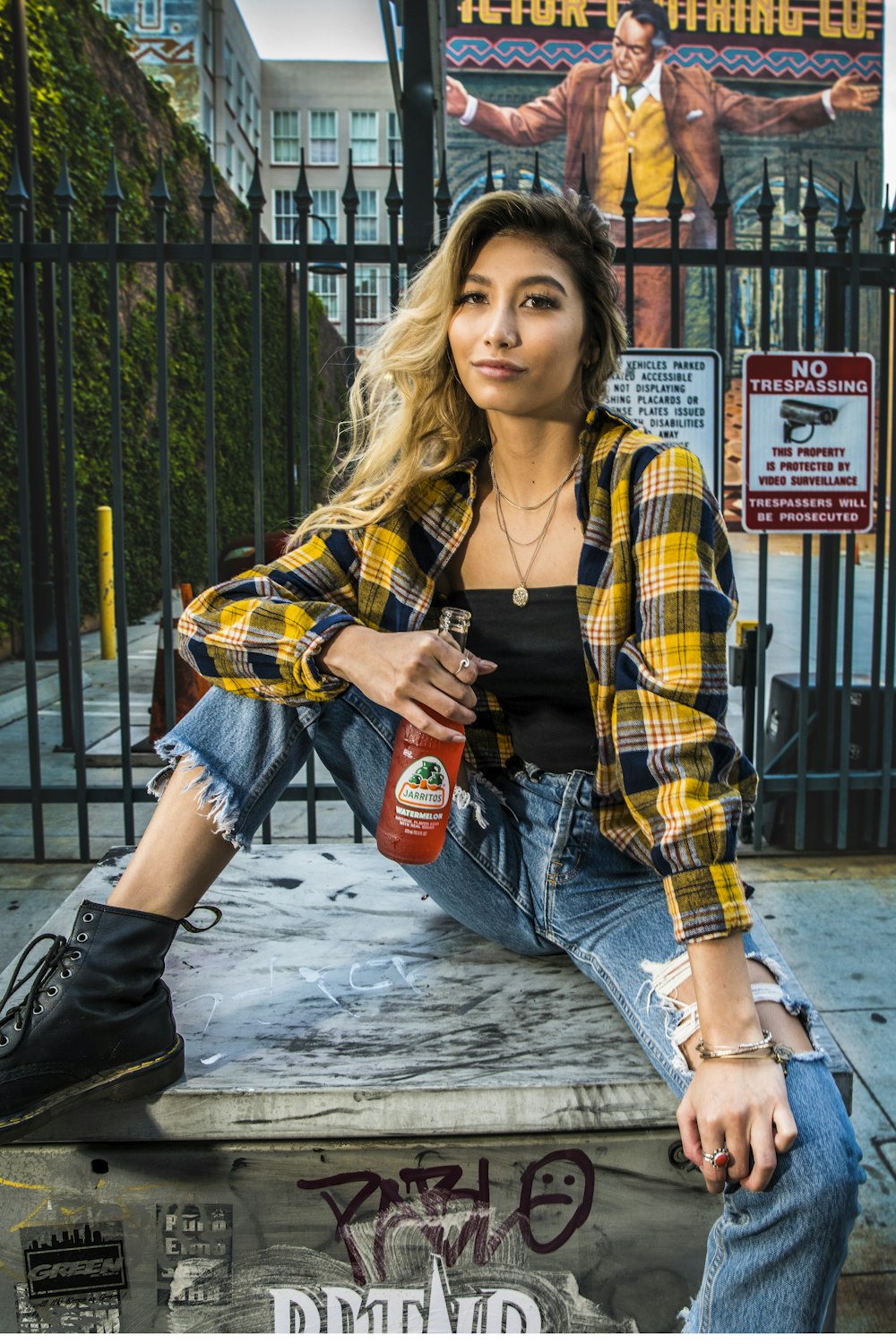 woman in yellow and black plaid dress shirt and blue denim jeans holding coca cola bottle
