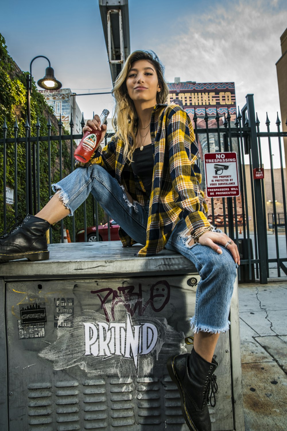 woman in yellow black and white plaid scarf and blue denim jeans sitting on brown wooden