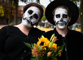 woman in black shirt wearing white mask holding yellow flowers