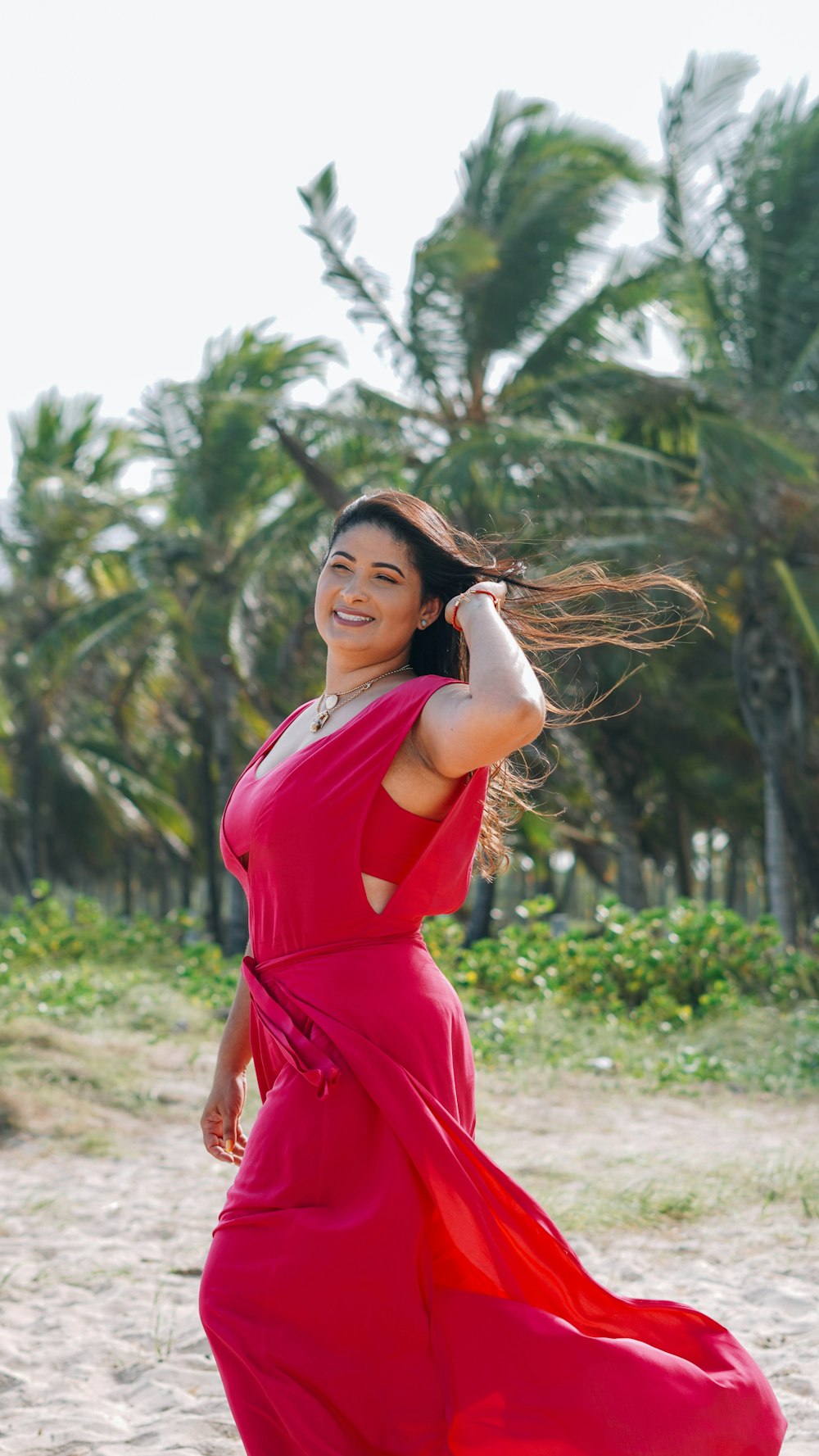 woman in red dress standing near green plants during daytime