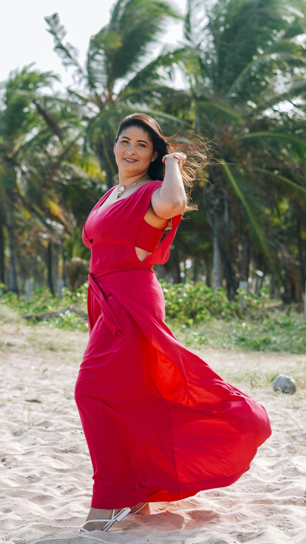 a woman in a red dress is dancing on the beach