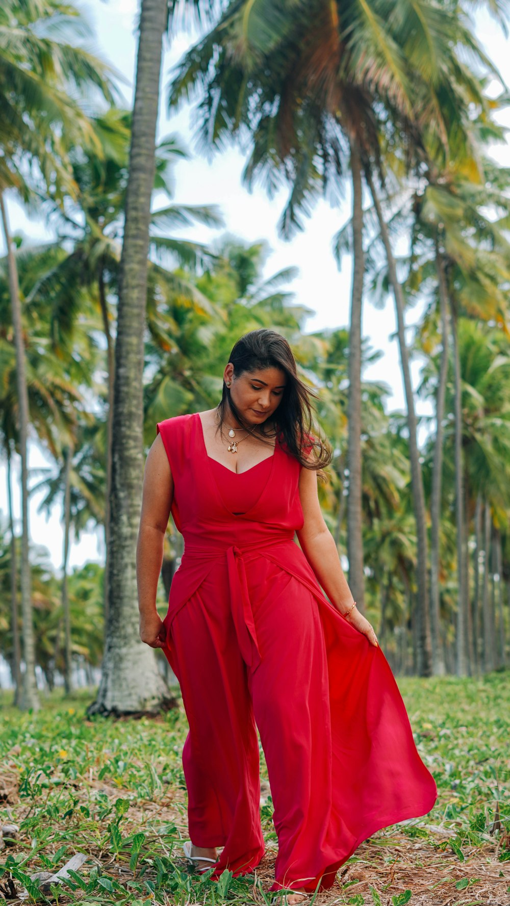 woman in red sleeveless dress standing near palm trees during daytime