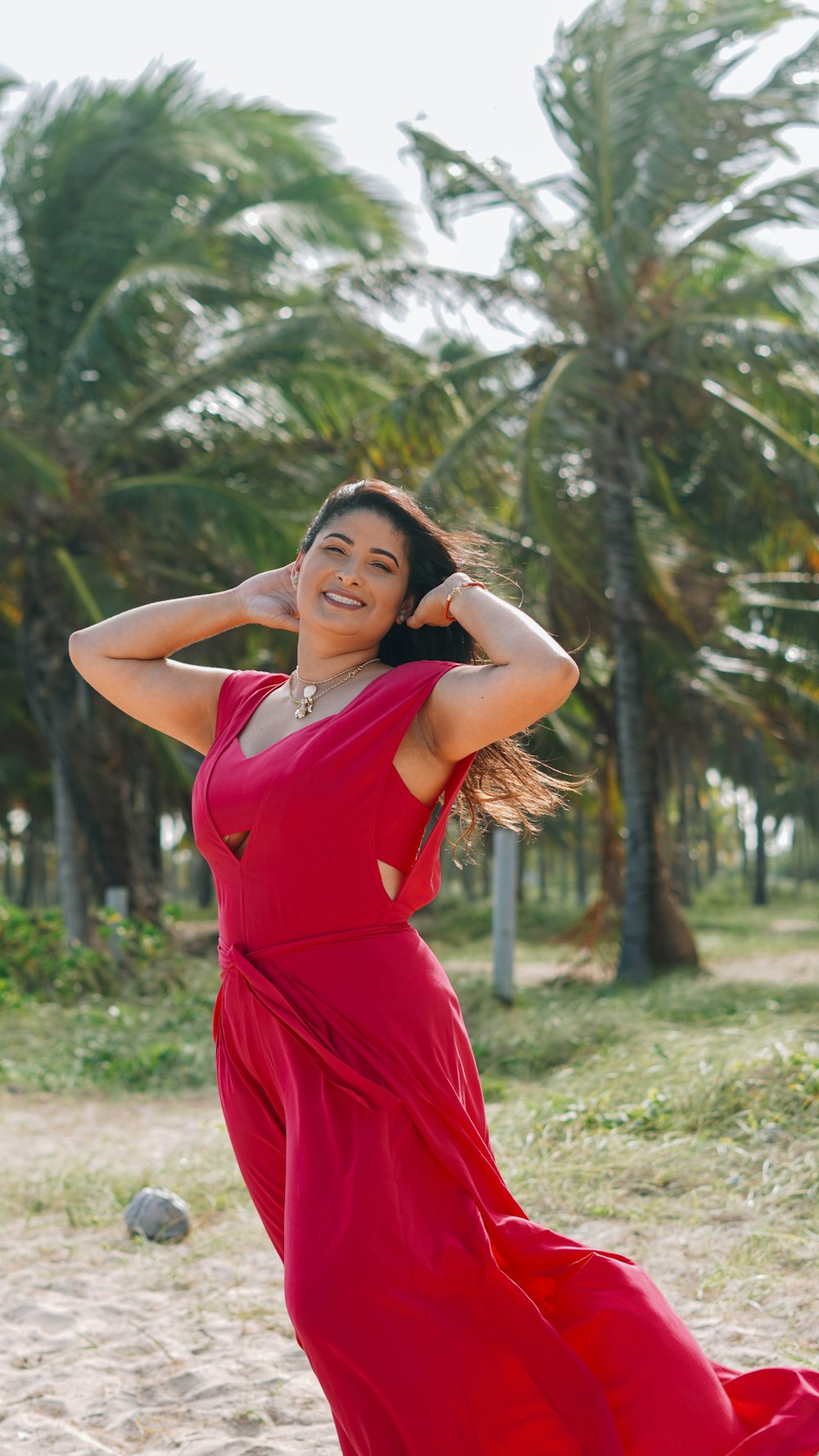 woman in red sleeveless dress standing near green trees during daytime