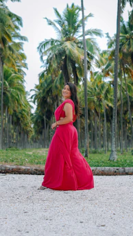 Elegant woman in a flowing dress walking along a sunlit Palm Beach promenade at golden hour.