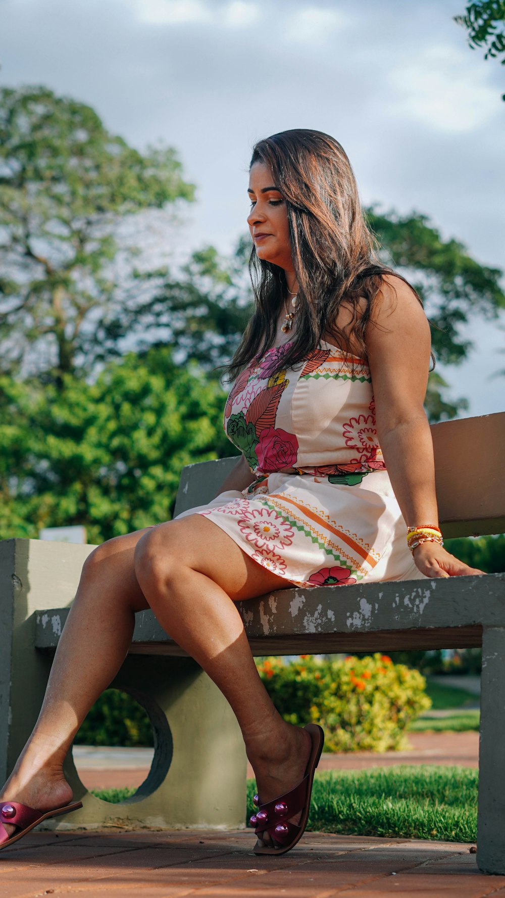 woman in red and white floral dress sitting on bench during daytime