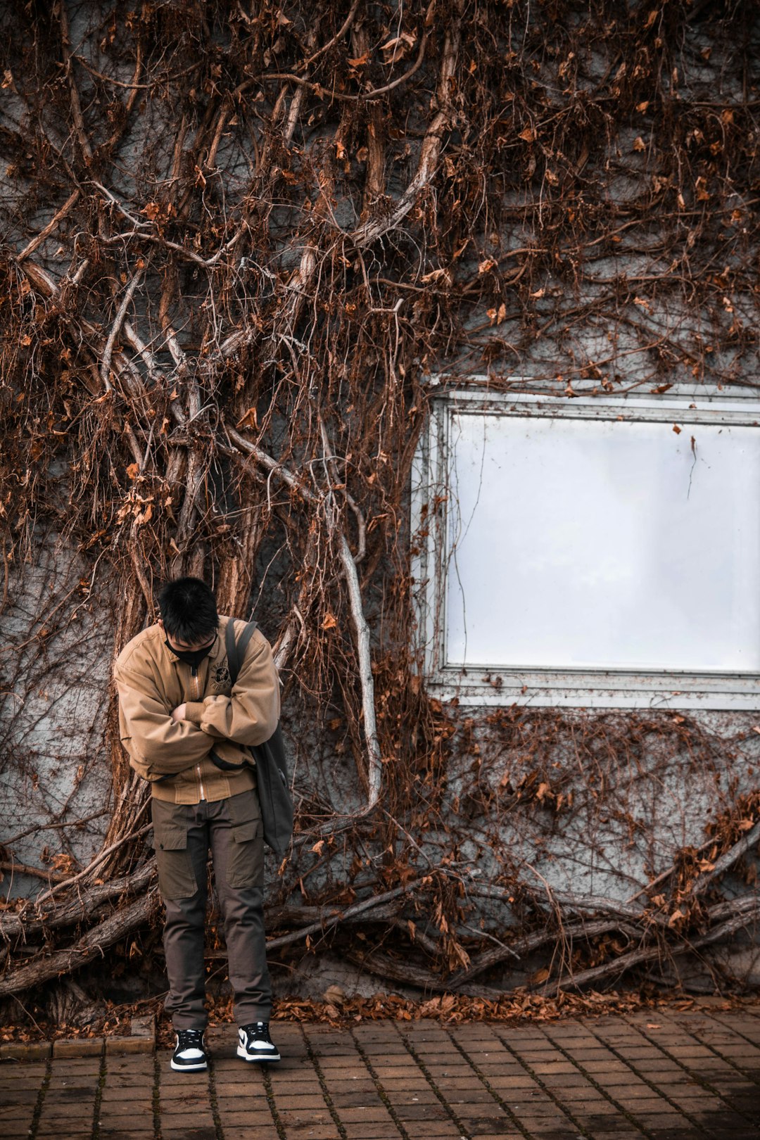 man in brown jacket standing in front of white wall