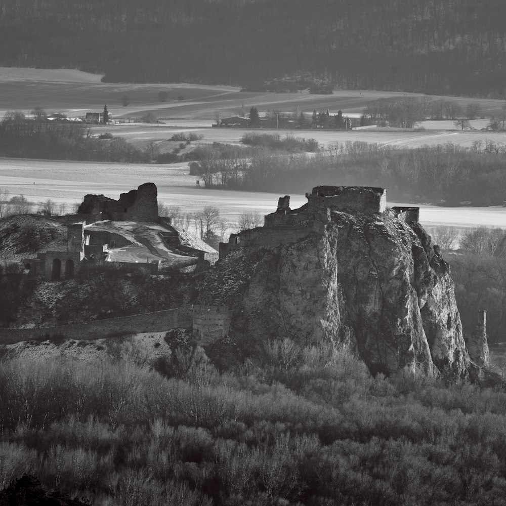 grayscale photo of rock formation near body of water