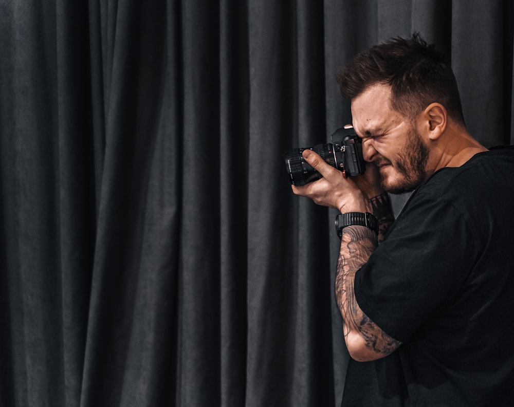 man in black shirt holding black dslr camera