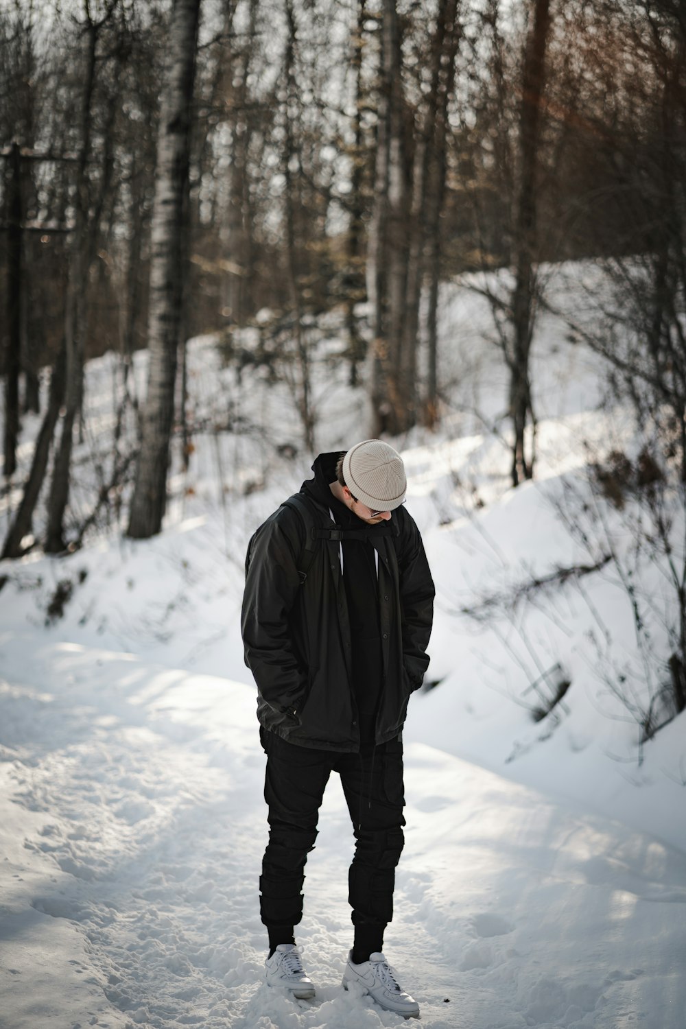 person in black jacket and white knit cap standing on snow covered ground during daytime