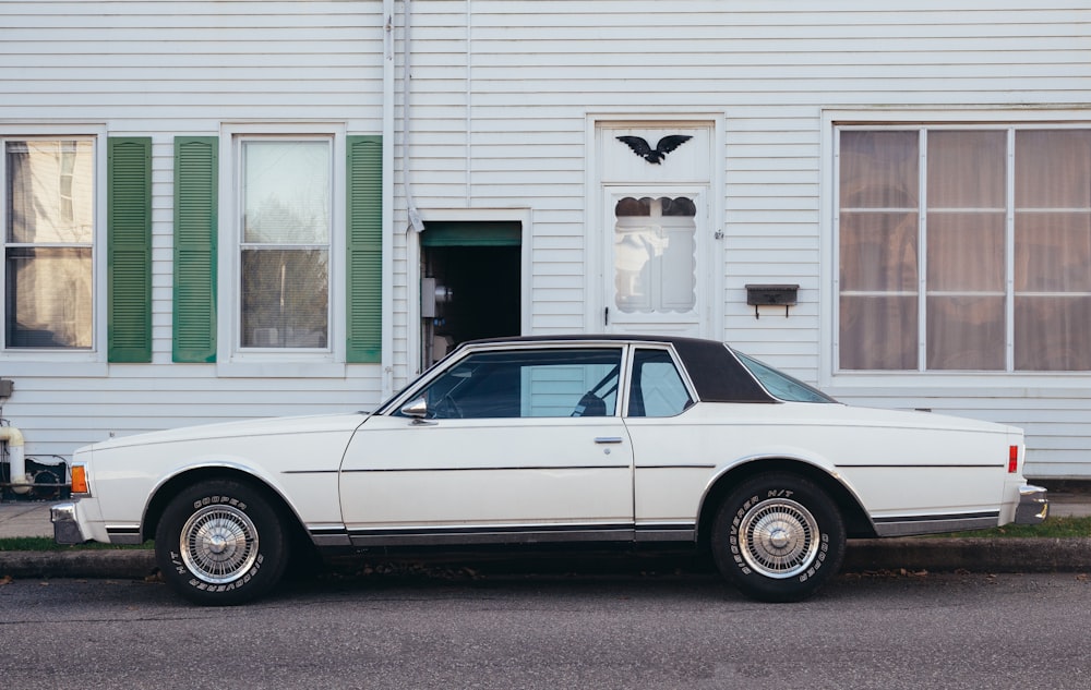 white sedan parked beside white wooden house during daytime