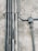 Multiple metal pipes are mounted along a textured concrete wall. The pipes vary in size and are arranged both vertically and horizontally, connected by clamps and a junction box.