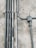 Multiple metal pipes are mounted along a textured concrete wall. The pipes vary in size and are arranged both vertically and horizontally, connected by clamps and a junction box.