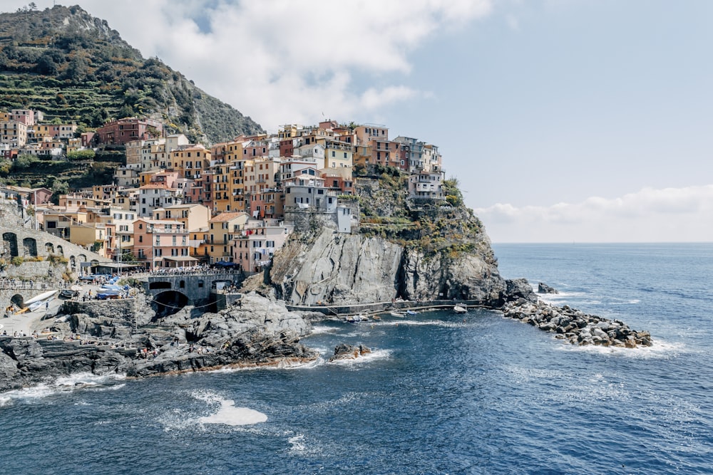 houses on rock formation beside sea under white clouds during daytime