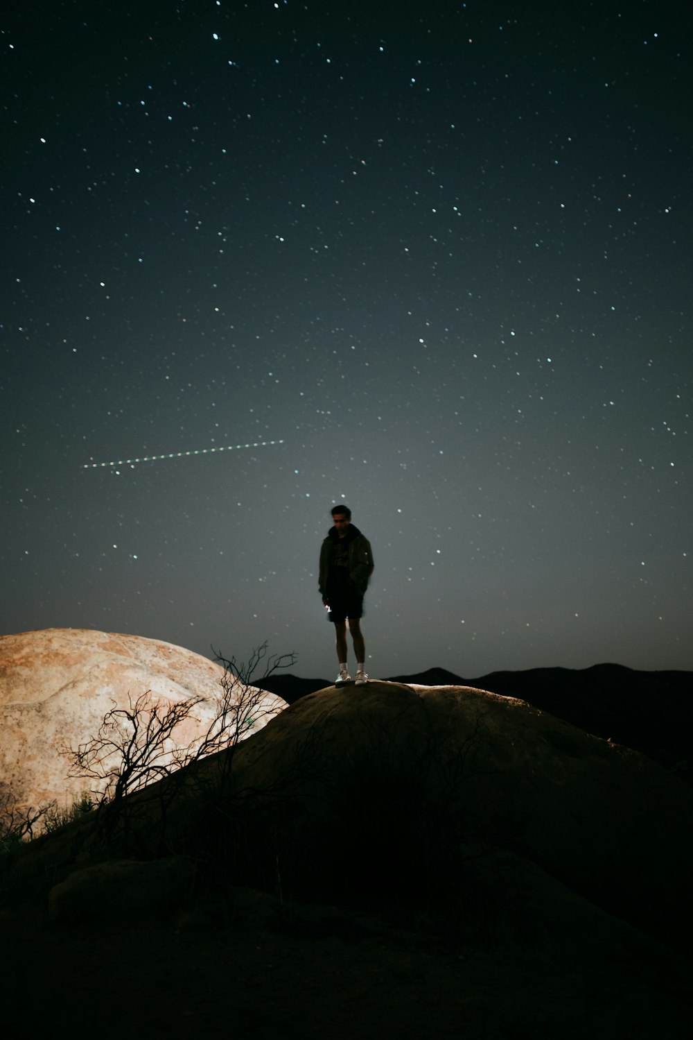 man in black jacket standing on brown rock during night time