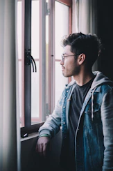 man in blue denim jacket wearing black framed eyeglasses