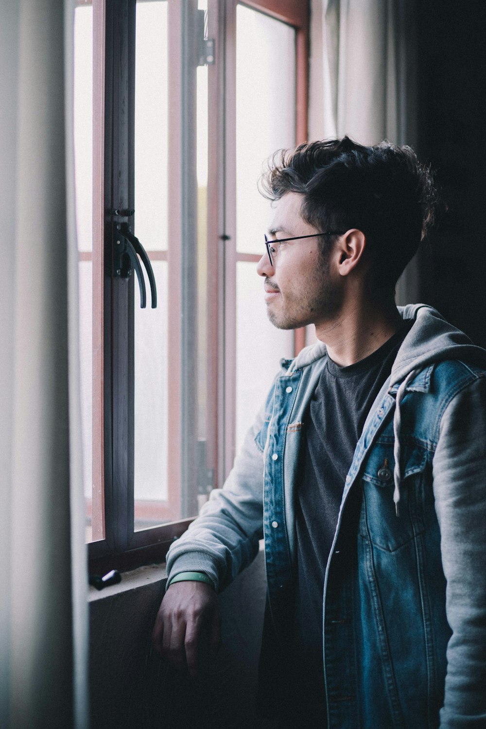 man in blue denim jacket wearing black framed eyeglasses