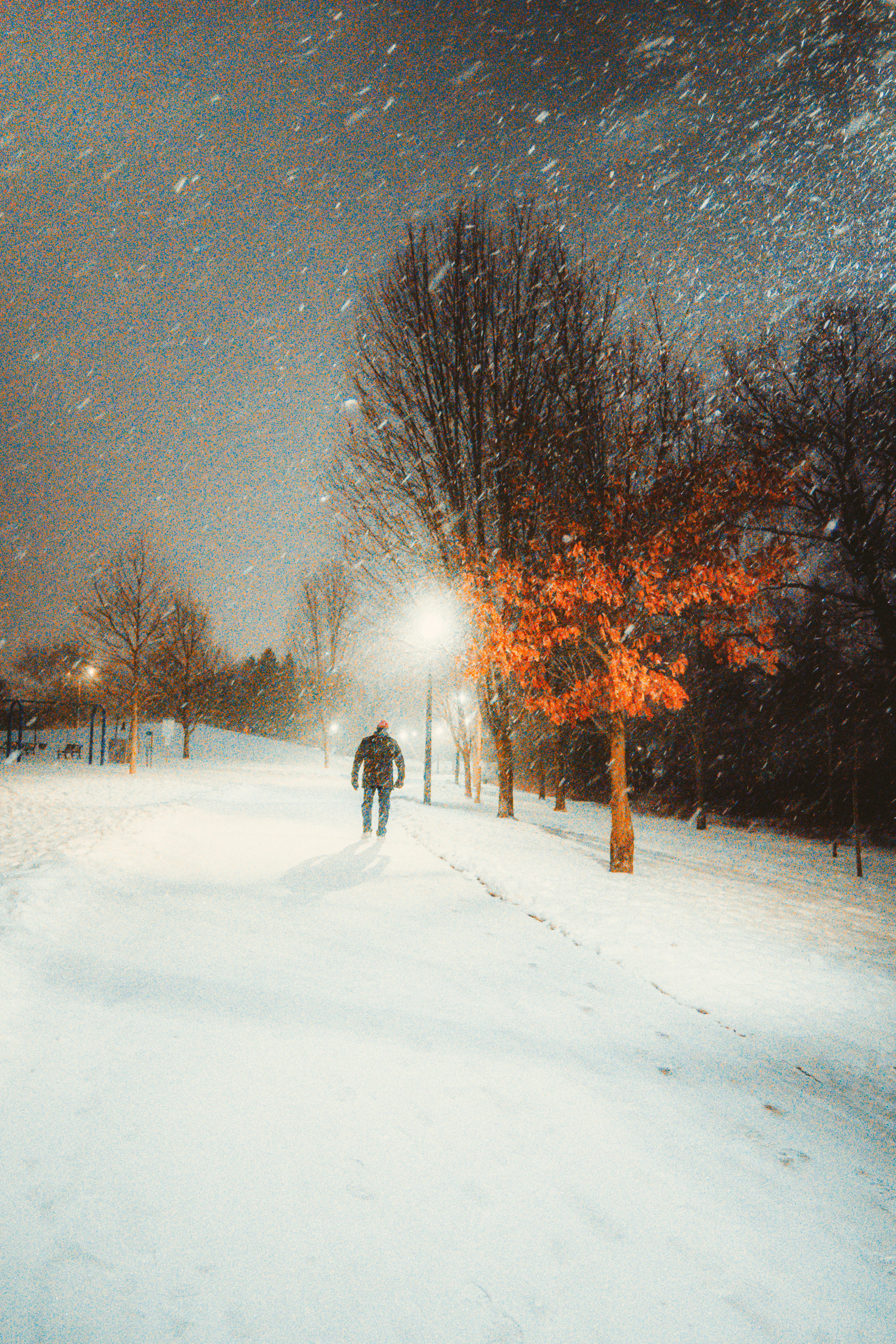 person walking on snow covered road during night time