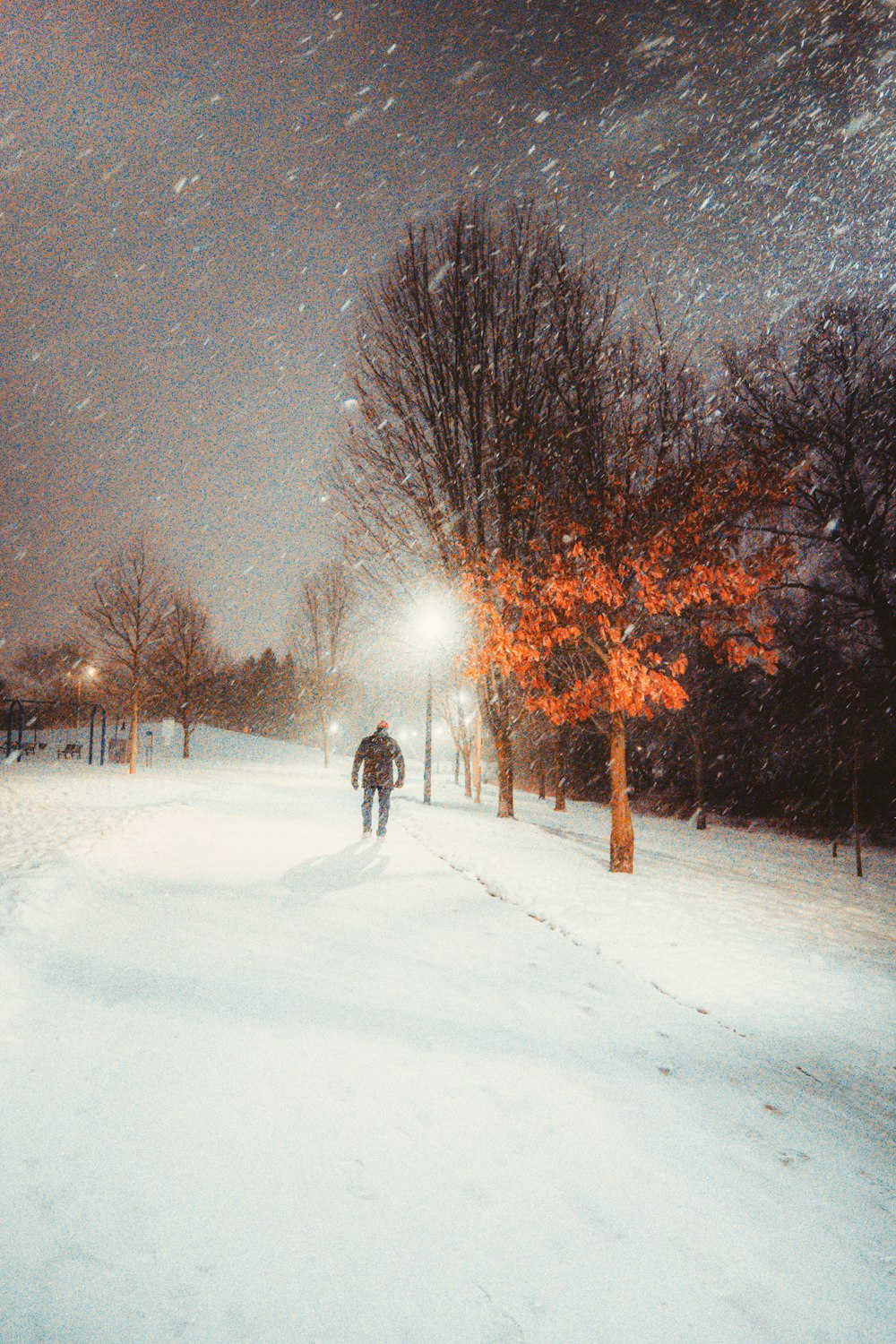 person walking on snow covered road during night time